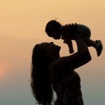 Image of a mum holding a child up in her arms