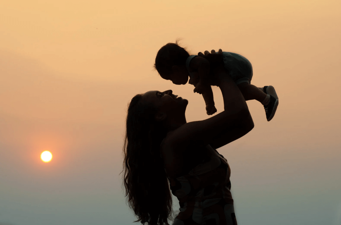 Image of a mum holding a child up in her arms